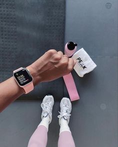 a person holding onto an apple watch on their wrist and wearing pink running shoes with white socks