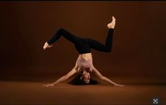 a woman is doing a handstand on her head with one leg in the air