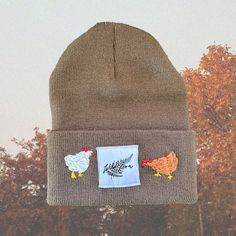 a brown beanie with two chickens on it