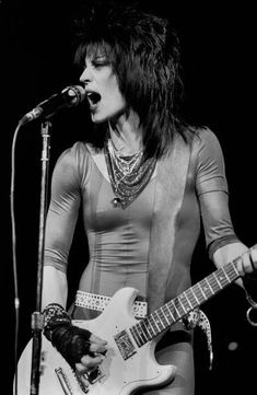 a woman singing into a microphone while holding a guitar