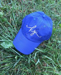 a blue hat laying in the grass on top of it's side with an embroidered logo