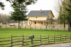 a large yellow house sitting on the side of a road next to a lush green field