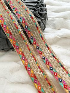 several different colored and beaded belts laying on top of a bed