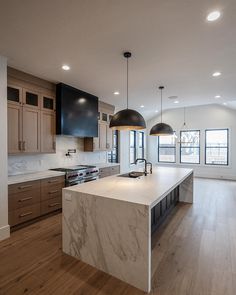 a large kitchen with an island and two pendant lights hanging from it's ceiling