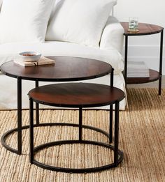 two tables sitting on top of a rug in front of a white couch and coffee table