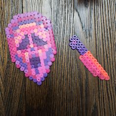 two pieces of plastic bead art on a wooden table next to scissors and beads