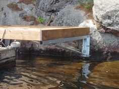 a wooden dock sitting on top of a body of water next to a rocky cliff