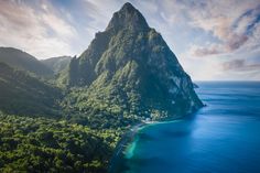 an island in the middle of some water with trees on both sides and mountains to the side