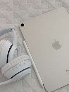 an apple laptop and headphones on a bed