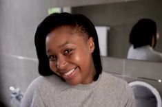 a woman smiling in front of a bathroom mirror