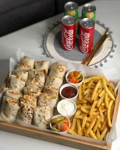 a tray filled with food next to two cans of soda and french fries on a table