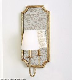 a wall mounted mirror on the side of a white wall next to a light fixture