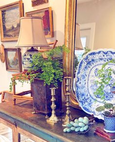 a table topped with plates and plants next to a mirror