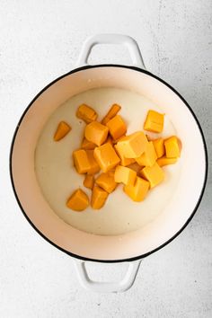 butter cubes in a pot with milk on the side and some other ingredients inside