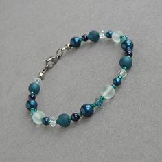 Showcasing lustrous glass pearls, sparkling crystals and frosted sea glass, this dark teal bracelet subtly twinkles in the light. This petrol blue bracelet has the versatility to be worn everyday as well as to be dressed up for more formal events.  This single strand bracelet measures 7.25 inches in length and is finished with a gunmetal-plated lobster clasp. I have added a 1 inch extension chain to allow you to adjust your beaded bracelet to fit.  Your peacock green pearl jewellery will be care Elegant Turquoise Beaded Bracelets For Party, Elegant Turquoise Crystal Bracelet With Round Beads, Elegant Turquoise Czech Glass Beaded Bracelets, Peacock Green Wedding, Green Pearl Jewelry, Green Wedding Jewelry, Chunky Stone Necklace, Teal Bracelet, Floating Pearl Necklace