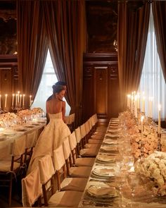 a woman in a wedding dress sitting at a long table