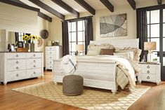 a white bed sitting on top of a wooden floor next to a dresser and mirror