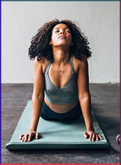 a woman is doing yoga on a mat with her eyes closed and hands in the air