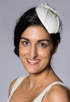 This unique deco bridal hat is strongly influenced by 1930s styling and takes elements from vintage bridal pieces. It was created with lightly padded off-white satin over a lightweight straw base, with a hand stitched soft feather trim and a glass bead and silver wire decoration. The piece is completed with a tailored satin bow. The reverse is finished with traditional millinery petersham and a comb bound with satin ribbon. The hat is 12.5cm at the widest point and 15cm long. The comb will sit s Vintage White Hat Headpiece, Vintage White Wedding Costume Hats And Headpieces, White Vintage Wedding Costume Hats And Headpieces, White Vintage Headpieces For Formal Occasions, White Vintage Headpiece For Formal Occasions, Vintage White Formal Headpieces, Vintage White Costume Hats For Wedding, Vintage White Costume Hats And Headpieces For Wedding, White Hat For Vintage Events