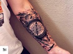 a man's arm with a compass and airplane tattoo on the left side of his arm