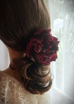 a woman with long hair wearing a flower in her hair and looking out the window