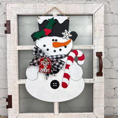 a snowman with a hat and scarf hanging on a window