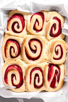 rolls with raspberry filling in a white baking dish on top of parchment paper