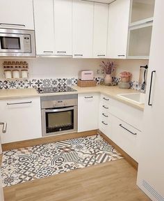 a kitchen with white cabinets and patterned flooring