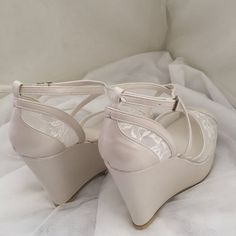 a pair of white high heeled shoes sitting on top of a bed