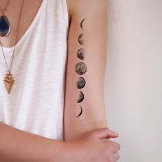 a woman's arm with phases of the moon on it