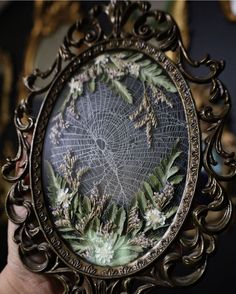 a hand holding an ornate mirror with flowers on it