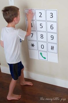 a young boy standing in front of a wall with a number puzzle on it's side