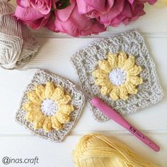 two crocheted squares with flowers and yarn next to them