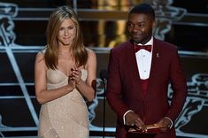 two people standing next to each other in front of an award podium and one person wearing a red tuxedo