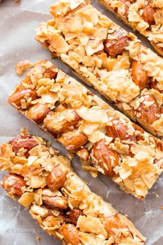 granola bars cut into squares on top of parchment paper with nuts and almonds