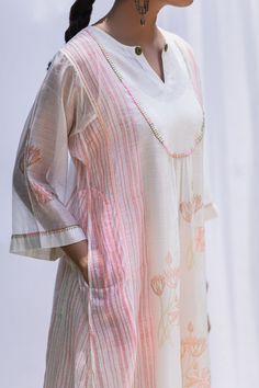 White long kurta with hand block-printed kurta motifs, pink stripes, floral motifs, gather detailing and blanket stitch over the yoke - sleeves. Comes with stripe pants and pink dupatta. 
Component: 3
Block Print, Embroidered
Neckline: Round
Sleeve Length: Three Quarter
Fabric: Kurta: Handwoven Chanderi, Pants: Cotton
Color: White,Pink
Flared sleeves
Gathered detail
Split neck
Note: Inner slip worn by the model is not for sale
 - Aza Fashions Long Kurta, Kurta For Women, Kurta Set For Women, Embroidered Neckline, Blanket Stitch, Comfort Wear, Kurta Set, Floral Motifs, Designer Wear