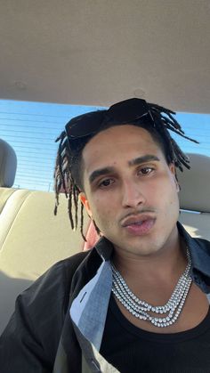 a man with dreadlocks sitting in the back seat of a car looking at the camera