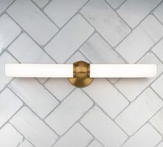 a close up of a bathroom light on a brick wall with white and gold accents