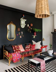 a living room with black walls and colorful pillows on the couches in front of a fire place