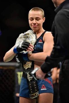 a woman holding a wrestling belt next to a man