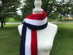 a white mannequin wearing a red, white and blue scarf on top of grass