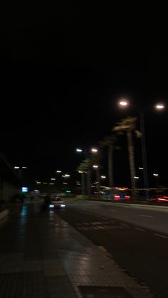 an empty city street at night with lights and palm trees