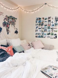 a white bed with lots of pillows and pictures on the wall