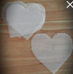 two white heart shaped doily sitting on top of a wooden table