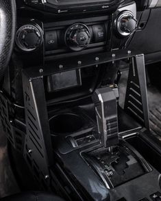 the interior of a car with an electronic device and steering wheel controls on it's center console