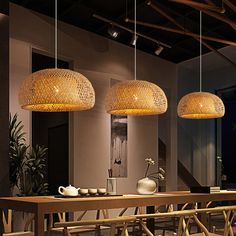 three lights hanging from the ceiling above a dining room table with chairs and vases