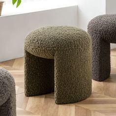 three stools made out of carpet sit on the floor next to a potted plant