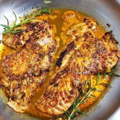 two pieces of chicken are in a pan with some garnish on the side