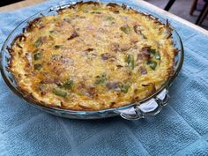 a casserole dish is sitting on a blue tablecloth with silver spoons