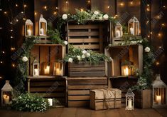 an arrangement of wooden crates with candles and greenery on the top, surrounded by string lights